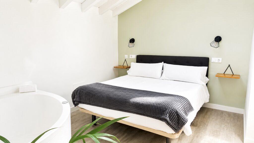 Dormitorio moderno con cama doble y bañera exenta