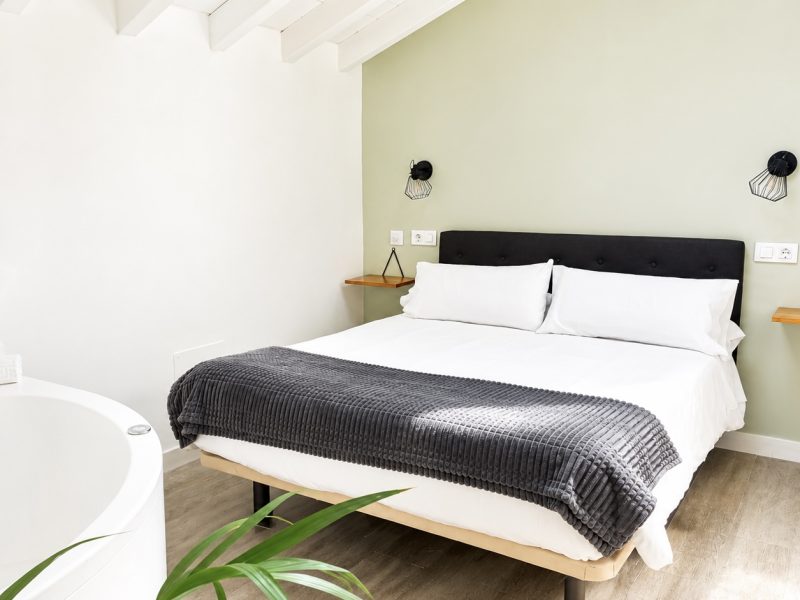 Dormitorio moderno con cama doble y bañera exenta