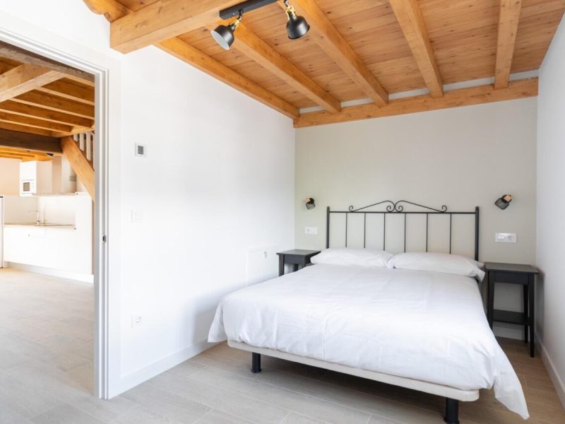 Chambre principale avec lit double et cuisine en arrière-plan, dans les appartements Somo et Loredo