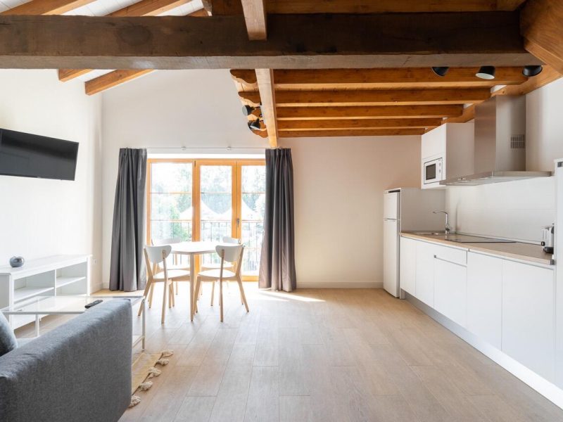 Salon-salle à manger avec cuisine ouverte et poutres apparentes dans les appartements Somo et Loredo, 80 m²