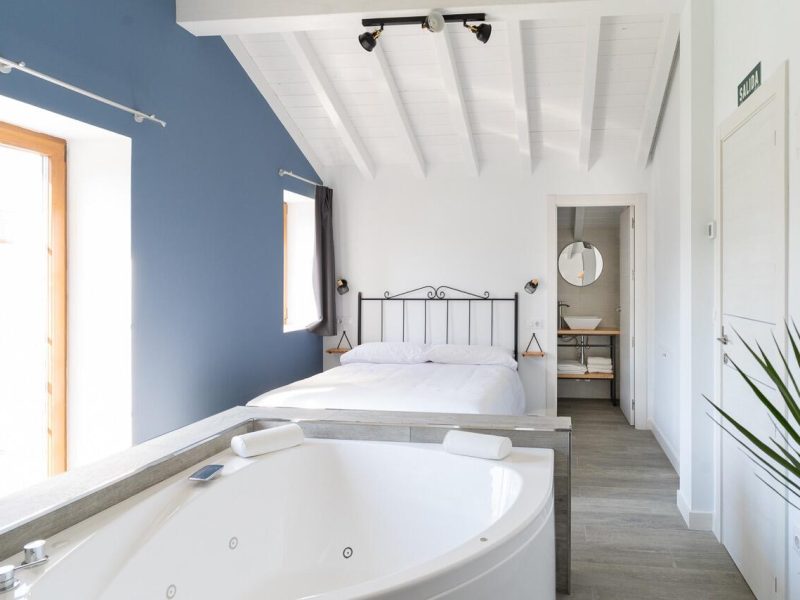 Bañera de hidromasaje doble junto a la cama en el ático Las Vistas, bajo techo abuhardillado